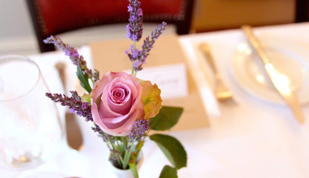 Vase of flowers on a table set with knife and fork